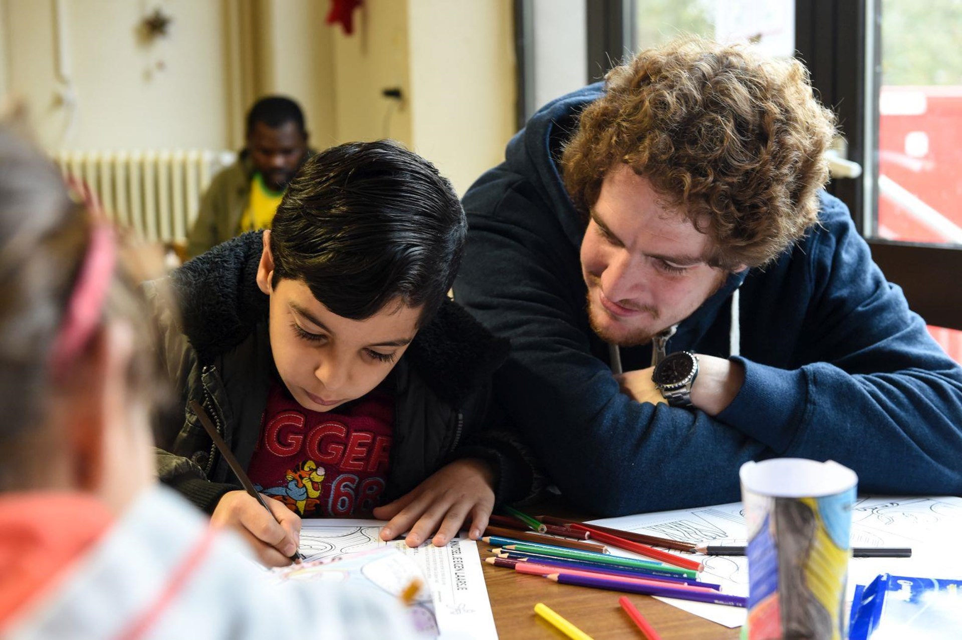Helfer und Flüchtlingskind malen